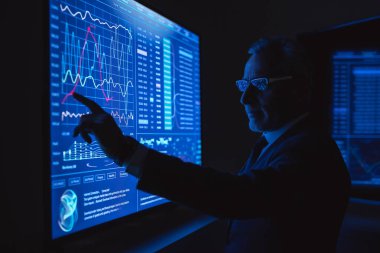 İşadamı karanlık ofisteki büyük sensör ekranında çalışıyor.