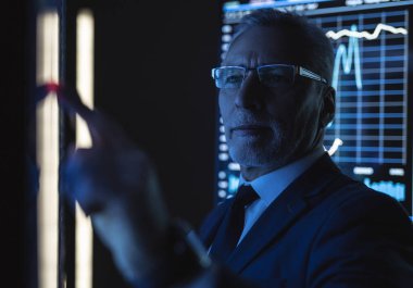 Yaşlı işadamı büyük sensör ekranı üzerinde çalışıyor.