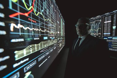 Karanlık laboratuardaki büyük sensör ekranında çalışan adam.