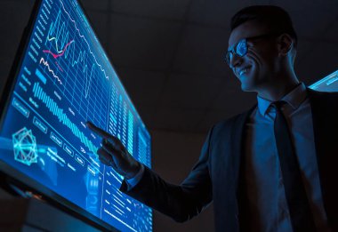 Karanlık laboratuardaki mavi ekranda çalışan gülümseyen iş adamı.