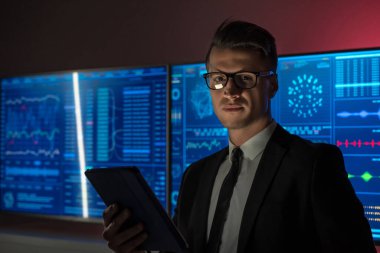 Genç işadamı kırmızı laboratuarda bir tablet tutuyor.