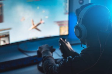Kişisel bilgisayarında video oyunları oynayan kulaklıklı adam.