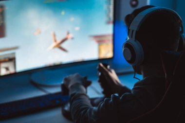 Kişisel bilgisayarında video oyunları oynayan kulaklıklı adam.
