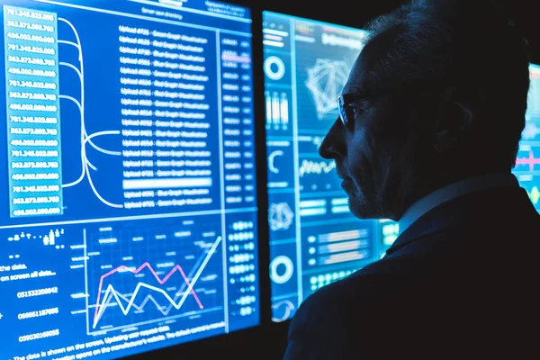 İşadamı karanlık ofisteki büyük sensör ekranında çalışıyor.