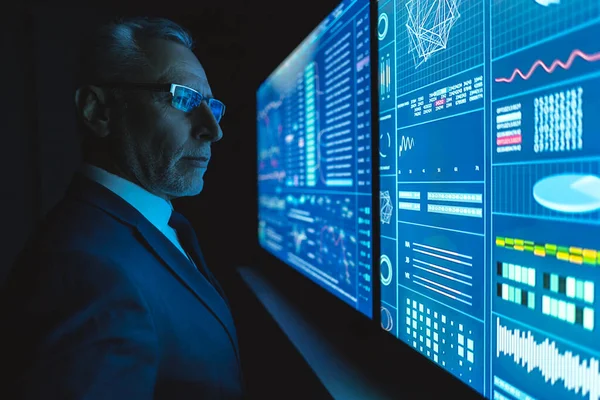 Karanlık odada mavi ekranın yanında duran adam.