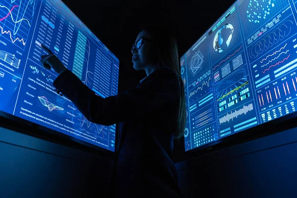 Mavi monitörün yanında duran iş kadını.