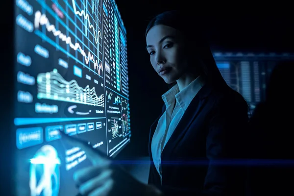 Kadın siyah ekranda grafiklerle çalışıyor.