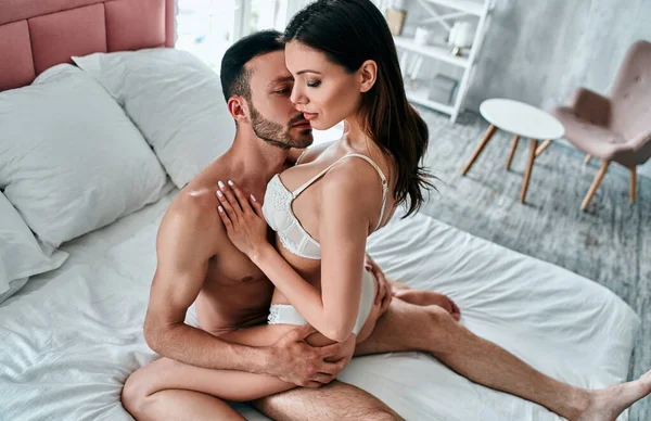 Kadın ve erkek iç çamaşırlarıyla yatakta sevişiyorlar.