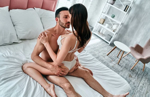 Kadın ve erkek iç çamaşırlarıyla yatakta sevişiyorlar.