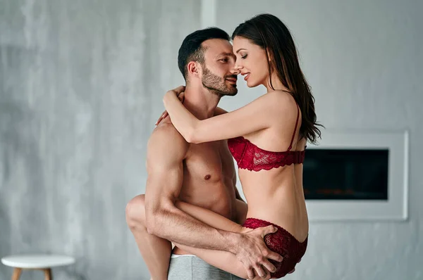 Adam odada iç çamaşırlı seksi bir kadın tutuyor.