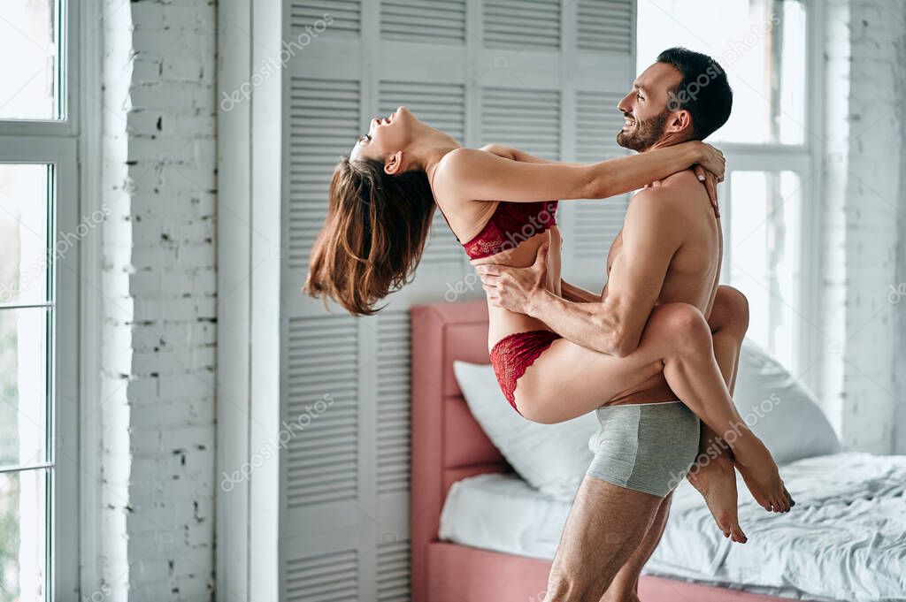 The happy man playing with a sexy woman in underwear in a bedroom