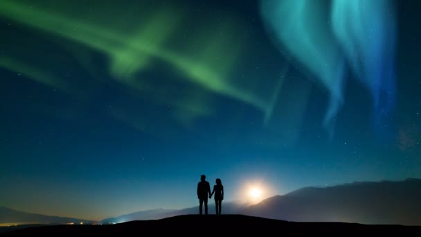 这对夫妇站在高山上 与北极光映衬着天空 时间流逝 — 图库视频影像