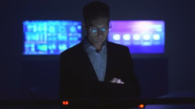 Karanlık odada tabletle çalışan adam.