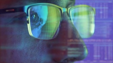 Gözlüklü adamın yüzü hologram arkaplanındaki ekrana bakıyor.
