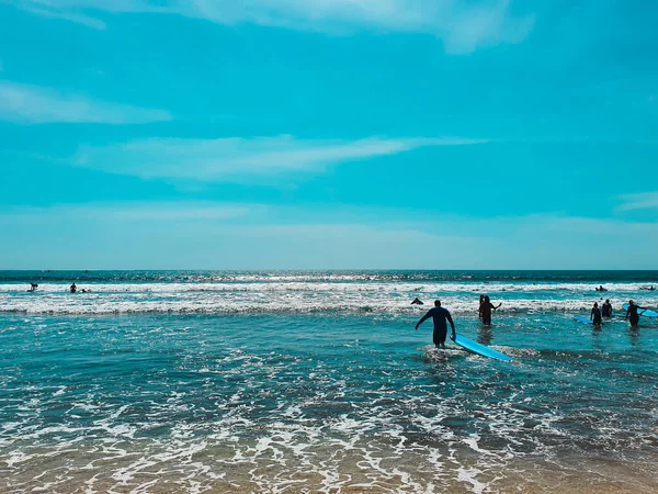 Sörfçüler Kuta Beach, Bali 'de okyanus dalgalarında sörf yapmaya hazır.