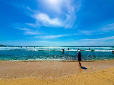İnsanlar öğle vakti Bali, Endonezya 'da sörfçülerle plajda.