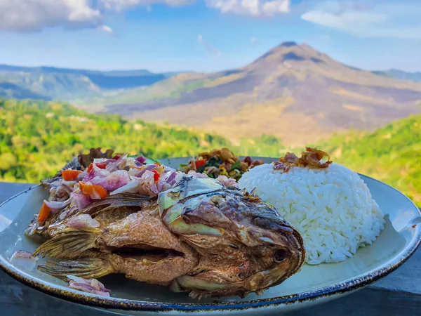 位于印度尼西亚巴厘岛的罗非鱼是以金塔曼尼火山为背景与米饭一起煎的 — 图库照片