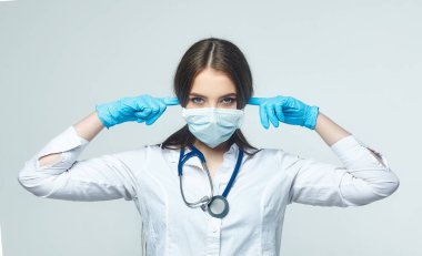 Covid19, koronavirüs, bir sağlık ve doktor konsepti. Duymak istemeyen bir kadın doktorun portresi. Virüs bulaşmasını önlemek için tıbbi maske takıyor.