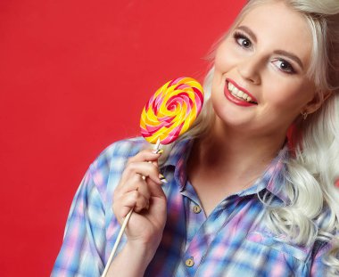 Büyük şekerli güzel sarışın, kırmızı arka planda poz veriyor.