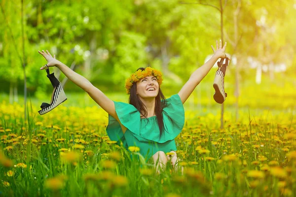 beautiful girl enjoys spring with a wreath of dandelions on her head