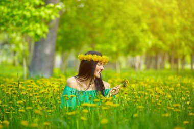 Güzel kız kafasında karahindiba çelengiyle baharın tadını çıkarıyor.