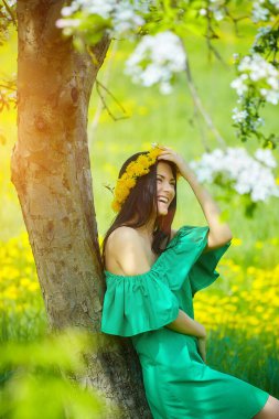 Güzel kız kafasında karahindiba çelengiyle baharın tadını çıkarıyor.