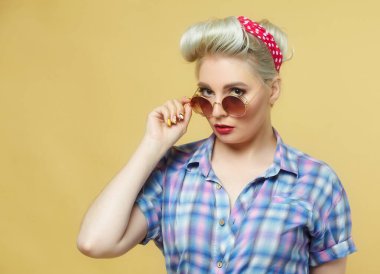 Sarı arka planda poz veren güzel sarışın.