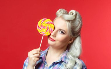 Büyük şekerli güzel sarışın, kırmızı arka planda poz veriyor.