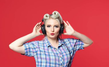 Kırmızı arka planda duran kulaklıklı güzel bir sarışın.