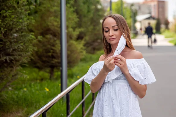 girl in the park takes off a medical mask