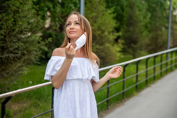 girl in the park takes off a medical mask