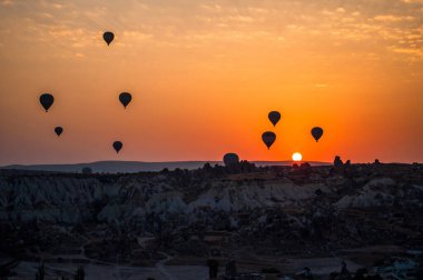 Kapadokya 'da güneş doğuyor. Goreme Vadisi 'nde sıcak hava balonları. Dağların üzerinden uçmak. Seyahat yeri. Renkli balon.