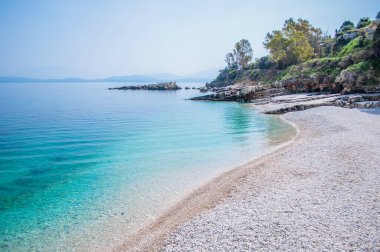 Yunanistan 'daki Korfu adası manzarası. Temiz turkuaz suyu ve ağaçları olan Rocky plajı. Körfezin güzel doğası. Yaz zamanı..