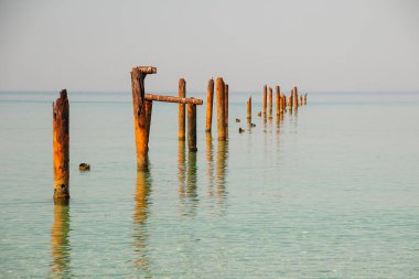 Mavi sakin suyu olan deniz burnu ve yaz günü yeşil yosunlu sıra sıra Rusty boruları. Eski iskeleden kalan paslı borular. Görüş açısı ufka açılıyor, insan yok. Sakin su.