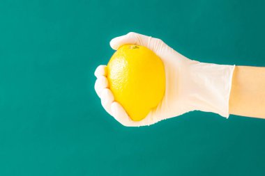 Limon tutan beyaz lastik eldivenli el. Coronavirus. Boşluğu kopyala.