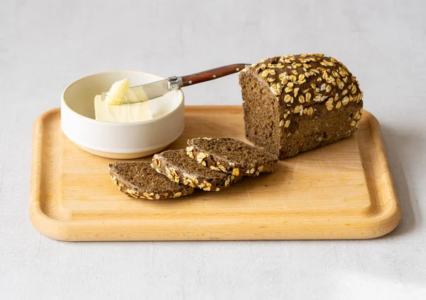 Dark whole grain bread and butter on cutting board. Healthy breakfast.