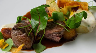 Orta pişmiş biftek, fırında patates, yeşil yaprak salatası.