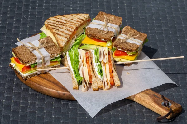 Sándwiches de club en una tabla de cortar. Almuerzo, desayuno o merienda saludables . — Foto de Stock