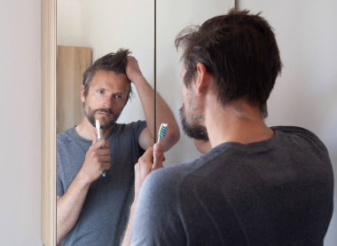 Adam endişeyle banyo aynasına bakıyor. 