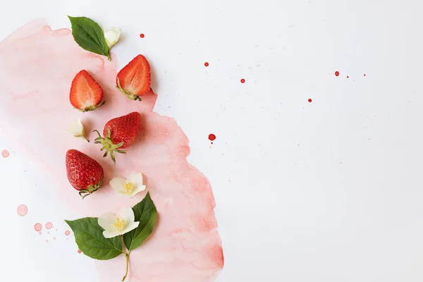 The creative composition is made of bright strawberries on a two-color watercolor background. Flat lay. The concept of food. Copy space.