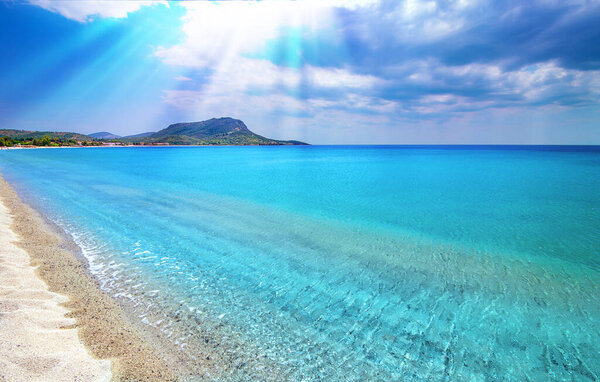 Blue sky, white clouds, sun rays, clear sea water background. Toroni beach, Sithonia, Greece