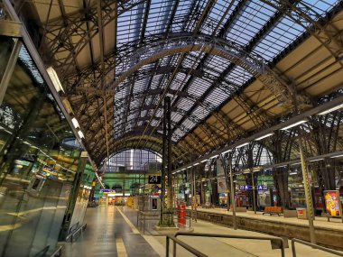 Frankfurt, Almanya 'daki tren istasyonunun içinde, büyük metal salonlu mimari, tren platformda duruyor ve iç mekanda çeşitli otomatlar bulunuyor (04 / 22 / 2019))
