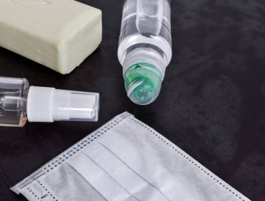 İki plastik atiseptik şişe, koruyucu bir yüz maskesi ve sabun eski, siyah bir ahşap masada yatıyor. Corona virüsü. Kovid 19. Salgın.