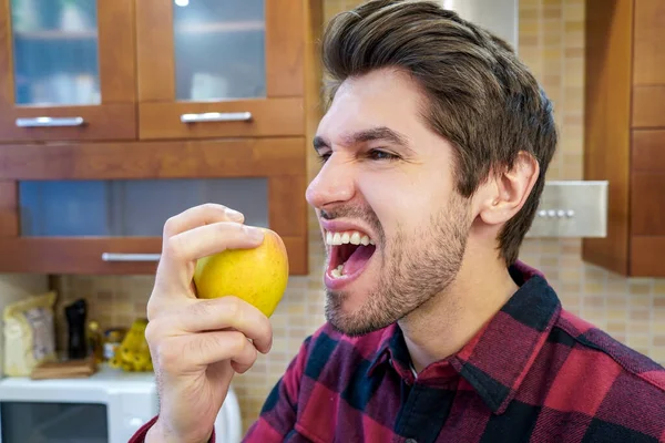 Retrato Jovem Cozinheiro Atraente Mordendo Uma Maçã Cozinha Usando Uma — Fotografia de Stock