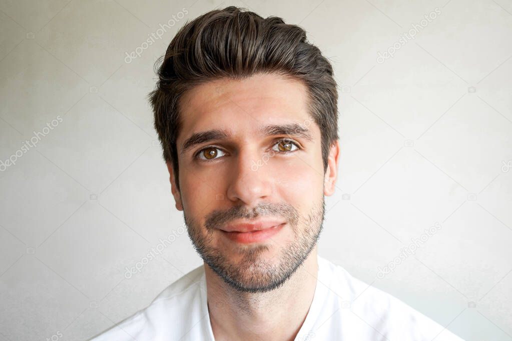 Portrait of a young gorgeous man with a cute smile and a beard with a perfect skin and hairstyle