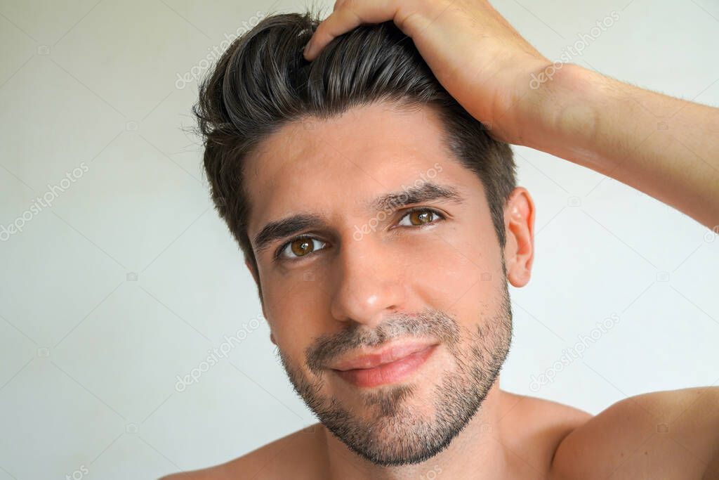 Young stunning latin man with a perfect skin is holding his hair