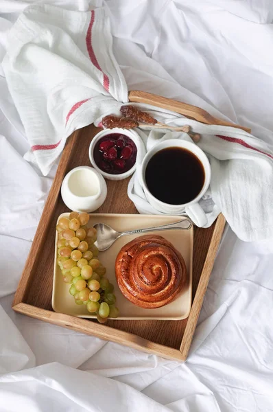 Breakfast on white bed sheets in hotel room. Close up of wooden