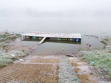 Nehirdeki araçlar için su platformu ve garaj yolu. Suyun kenarında yoğun bir sonbahar sisi..