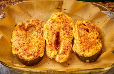 Fırındaki çıtır peynirin altında pişirilmiş gurme somon bifteği.