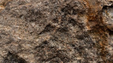 Gri-kahverengi granit. Granit kayalar. Paslı arka plan. Renkli kaya arka planı. Sert kırmızı kahverengi desenli kaya duvar arkaplanı. Grunge Soyut Taş Yüzeyi.